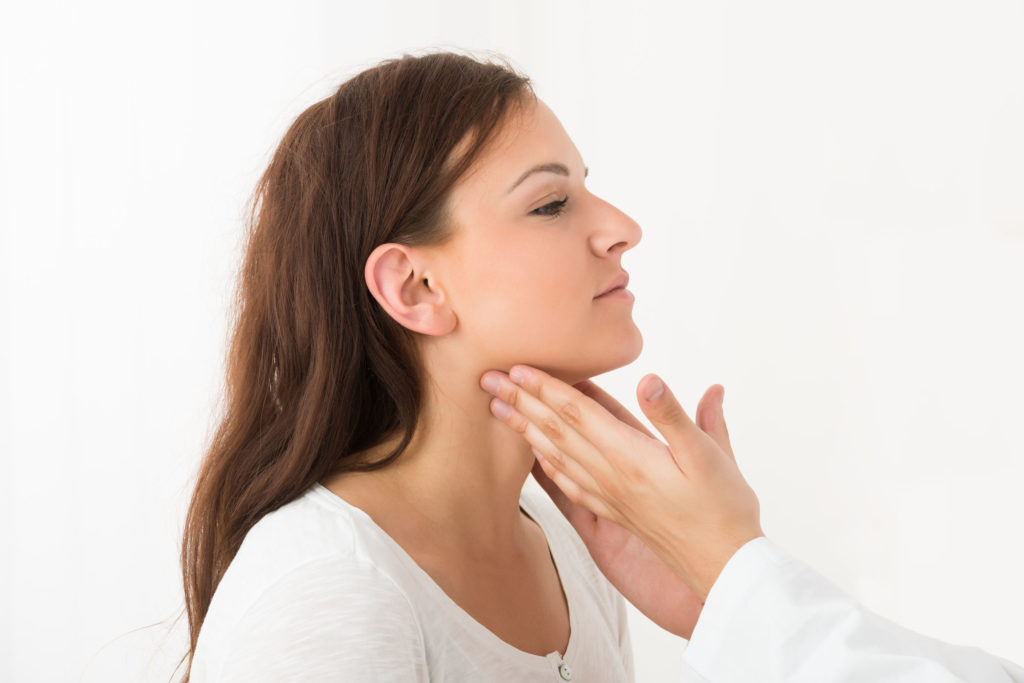 Close-up Of A Doctor's Hand Touching The Throat Of A Female Patient In The Clinic